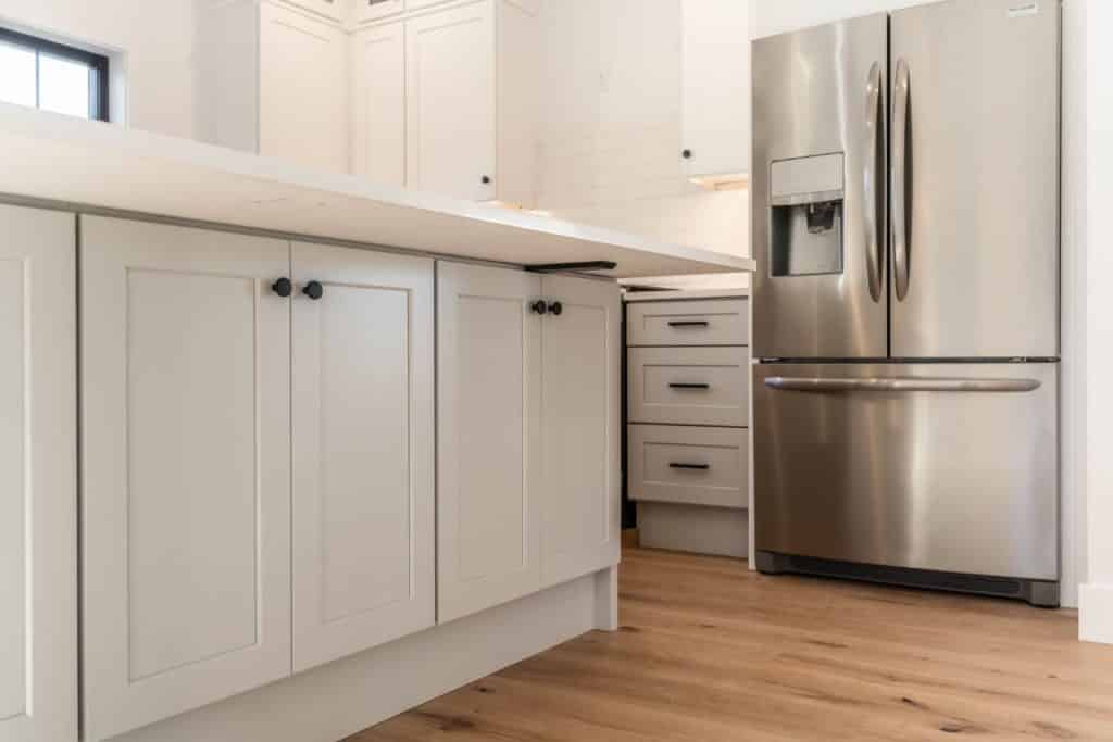 The center island of a recently redesigned kitchen sits above a hardwood floor with a natural grain.
