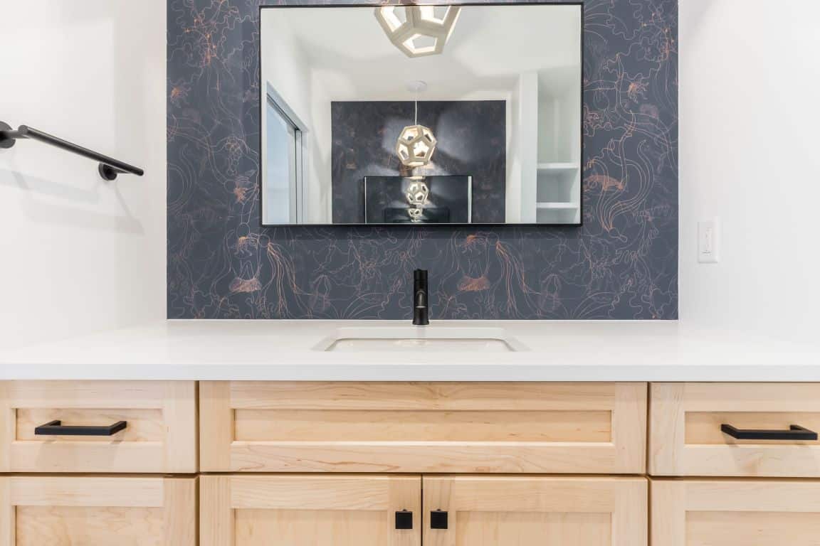 Hexagon pendant lights are reflected in the mirror that hangs above a bathroom vanity.
