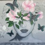 Graffiti of a woman's face. The top one-third of her head turns into flowers and butterflies